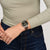 Swatch Chronographen-Armbanduhr am Handgelenk mit braunem Lederband und schwarzen Zählern