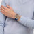 Herren-Uhr mit blauem Armband am Handgelenk, braunes Zifferblatt und Leuchtzeiger