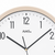 Gros plan d'une horloge murale avec un bord beige et un cadran blanc, chiffres noirs