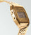 Montre Casio Vintage dorée avec bracelet en métal, boîtier latéral et affichage de l'alarme LCD.