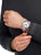 Silberne Herrenuhr am Handgelenk mit weißem Zifferblatt und Metallarmband