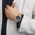 Montre unisexe au poignet : cadran bleu avec lunette dorée et bracelet foncé