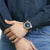 Montre bracelet au poignet avec cadran bleu, lunette dorée et bracelet bleu foncé