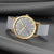 Montre unisexe avec cadran gris clair, lunette dorée, aiguilles rouges, bracelet gris.