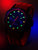 Montre homme avec boîtier noir et bracelet en silicone rouge, aiguilles lumineuses