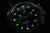 Montre bracelet pour homme, gros plan : lueur verte sur cadran noir
