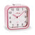 Réveil compact rose avec cadran blanc, aiguilles analogiques et couvercle supérieur