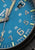 Detail der Herrenarmbanduhr: blaues Zifferblatt mit Ziffern und Zeigern