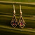 Boucles d'oreilles dorées avec pierre sombre dans un cadre carré en fil de fer, forme goutte.
