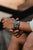 Montre bracelet pour homme avec cadran noir au poignet, main indiquant l'heure