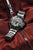 Chronographe pour homme au poignet avec cadran noir et bracelet en acier inoxydable argenté.