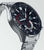 Chronographe pour homme, vue latérale : cadran noir, boîtier et bracelet en acier inoxydable argenté.