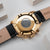 Holzkern Armbanduhr mit goldenem Gehäuseboden und schwarzem Lederband, darunter Buckle