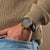 Holzkern Armbanduhr am Handgelenk: schwarzes Lederband, goldenes Gehäuse, Marmorzifferblatt