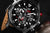 Herrenarmbanduhr mit schwarzem Zifferblatt und roten Akzenten, Chronographen-Design