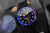 Montre homme avec cadran noir, index violets et bracelet noir