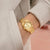 Goldfarbene Damenarmbanduhr mit Metallband und weißem Ziffernblatt am Handgelenk