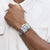 Montre bracelet pour homme en acier inoxydable au poignet, bracelet argenté à maillons imbriqués.