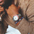 Herrenarmbanduhr am Handgelenk, silbernes Gehäuse, weißes Zifferblatt und blau-rote Lünette