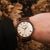 Holzkern-Armbanduhr am Handgelenk mit braunem Holzarmband und beigem Zifferblatt