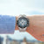 Chronographe sportif Festina au poignet avec cadran noir et bracelet beige