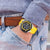 Montre pour homme au poignet : bracelet jaune, cadran noir, look sportif