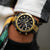 Herren-Chronograph mit schwarzem Zifferblatt und goldfarbener Lünette am Handgelenk