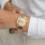 Goldfarbene Damenarmbanduhr am Handgelenk mit Metallband und mehrfarbigem Zifferblatt