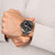 Herrenarmbanduhr am Handgelenk mit schwarzem Zifferblatt und Metallarmband