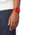 Montre homme avec bracelet en caoutchouc rouge et cadran rouge, portée au poignet sur le côté.
