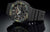 Montre homme avec bracelet en plastique noir et boîtier rond, cadran camouflage