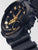 Casio G-Shock Montre Femme, vue détaillée du boîtier noir avec des éléments dorés