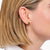 Goldfarbene Tropfen-Ohrstecker am Ohr, schimmernde, gebogene Form; Thomas Sabo