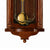 Détail de l'horloge murale en bois marron : cloche dorée et ornements floraux