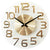 Horloge murale ronde en verre avec chiffres dorés, deux aiguilles et logo JVD
