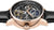 Montre homme avec lunette or rose, mouvement automatique visible et bracelet en cuir noir