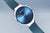 Armbanduhr im 3/4-Ansicht: blaues Zifferblatt, schlanke Zeiger, Milanaisearmband
