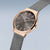 Montre pour femme en gros plan : lunette or rose, cadran gris foncé, bracelet milanais
