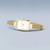 Montre pour femme avec boîtier rectangulaire et cadran blanc sur bracelet milanais doré.