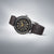Montre Seiko pour homme de côté : bracelet en cuir marron, lunette noire, cadran sombre avec index dorés