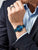 Armbanduhr am Handgelenk mit blauem Zifferblatt und Milanaiseband