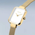 Montre femme avec boîtier rectangulaire, cadran blanc et bracelet milanais doré.