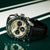 Montre pour homme avec cadran beige, bracelet en cuir noir et poussoirs de chronographe.