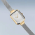 Montre femme avec cadran rectangulaire argenté, bords plaqués or, bracelet milanais