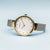 Montre femme en vue de côté : lunette dorée, bracelet milanais argenté