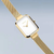Montre pour femme en vue de côté : boîtier rectangulaire avec lunette et bracelet dorés.
