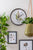 Wanduhr am Wandmontage-Setup mit botanischem Blätterdesign im runden schwarzen Rahmen