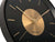 Détail de l'horloge murale : index dorés, cadran clair, aiguilles sombres.