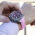 Montre chronographe pour homme au poignet avec bracelet en silicone rose et cadran noir.