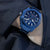 Montre chronographe pour homme au poignet avec cadran bleu et bracelet en métal